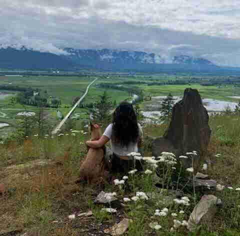 Amy Jefferson back to the camera. sitting on top of a hill enjoying the view