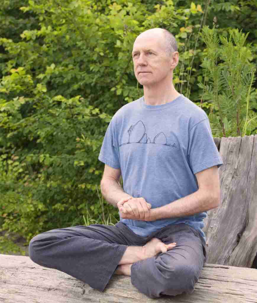 Bernie Clark a man. sitting crossed legged hands clasped at front mediating in the forest. for online meditation course. yoga blog vedic meditation training