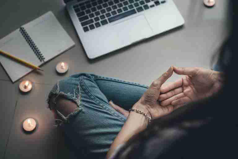 top view of a woman crossed legged hands on lap computer is visible doing an Online Meditation Course. Guided Vedic Meditation training