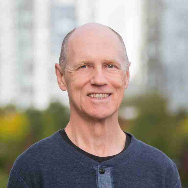 bernie clark wearing a blue shirt portrait photo with a blurred backgorund. Bernie is a YACEP Yin Yoga Teacher Trainer