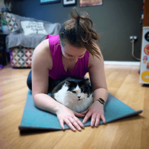 Jennifer, a caucasian women, online yoga teacher in her home with her black & white cat.