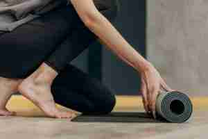 close up of a woman rolling out a yoga mat in a yoga class