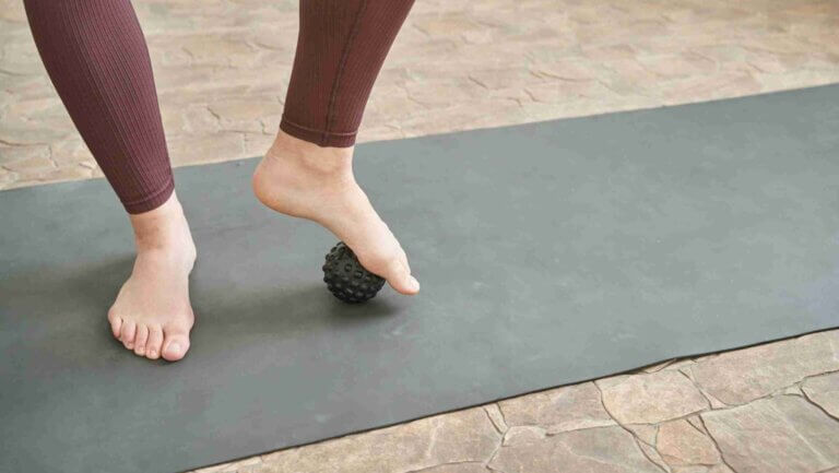a person using a ball under their foot to benefits of stretching toes. yoga blog