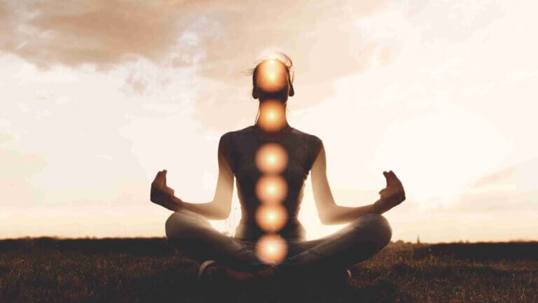 image of a man sitting. all chakras are illuminated by using mudras and mantras to unblock a chakra
