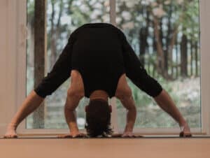 Man doing a wide legged forward fold for root chakra healing