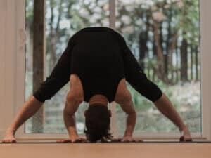 man doing a wide legged forward bend for purple chakra balancing