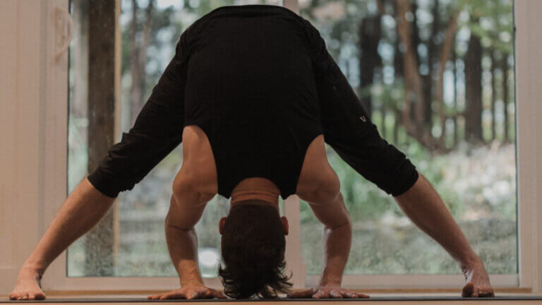 man doing a wide legged forward bend for, Sahasrara, purple chakra balancing. Kevin Parenteau Ashatnaga Yoga Teacher