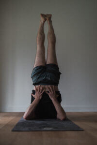 man doing a shoulder stand for purple chakra balamncing