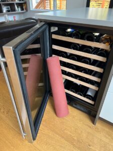 wine fridge open with a yoga mat. diy yoga mat storage
