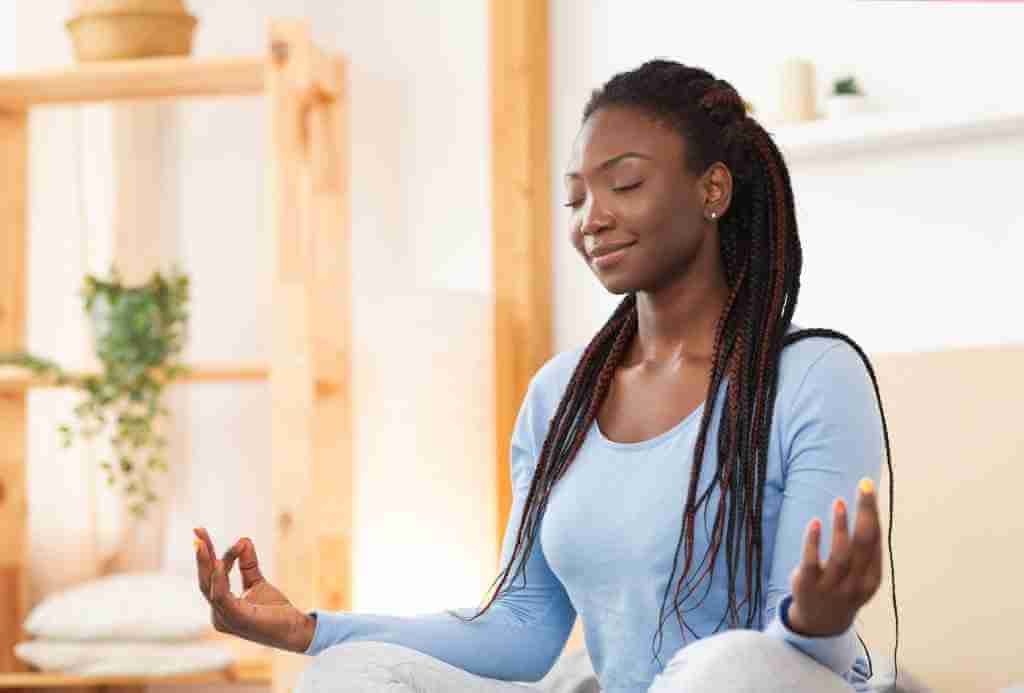 African American woman. sitting in meditation practicing mudras and mantras