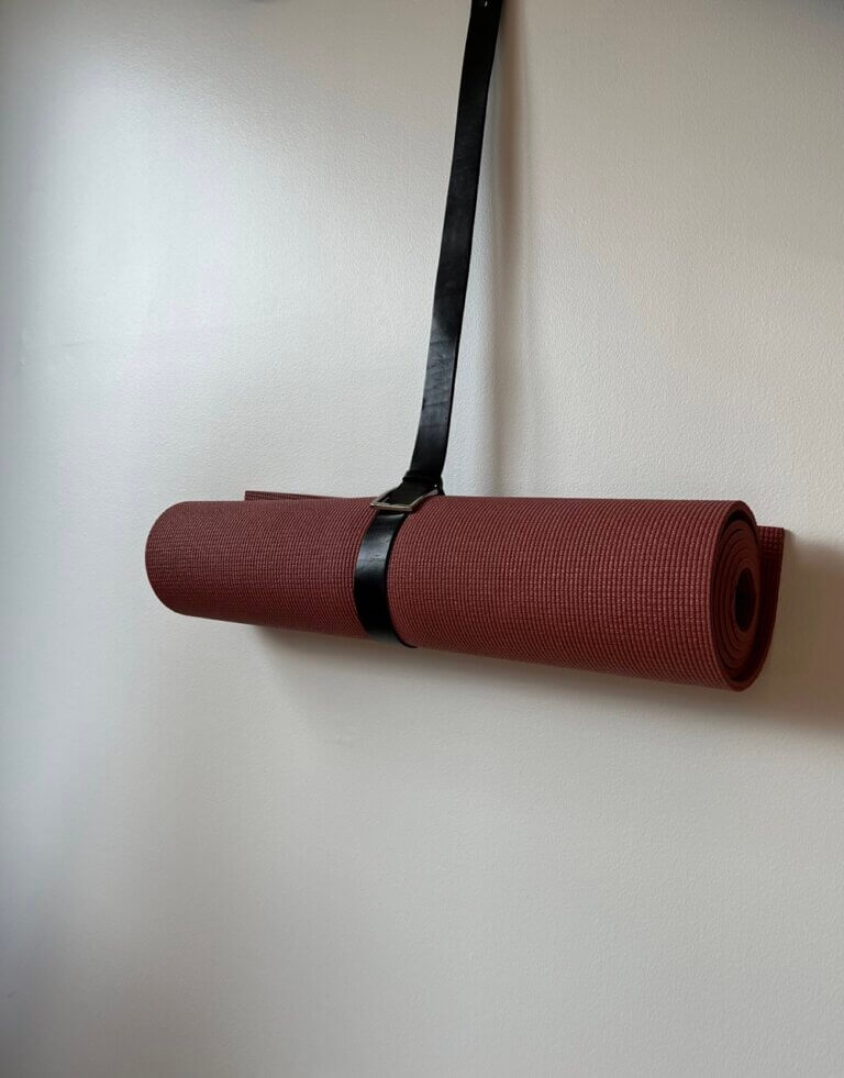 pants belt wrapped around a yoga mat and pinned to the wall for DIY yoga mat storage