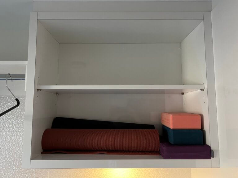 two shelf shelving unit. white with two yoga mats and two yoga blocks a DIY yoga mat storage