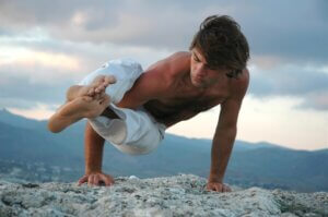 Young man doing an ashtavakrasana. Hand standing (variant) inspirted by best yoga teacher quote