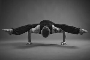 man doing a yoga arm balance. black and white photo. tacher quote