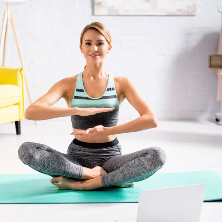 woman sitting on yoga mat practicing heart chakra mantras
