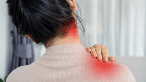 back closeup view of a woman holding her shoulder. shes's in pain. she is performing nerve gliding exercises shoulder