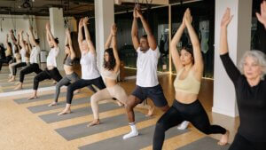 Inside a yoga studio. Group of yogi people doing yoga. Highlighting a person who practices yoga