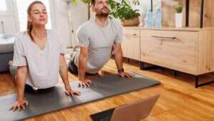 A man and woman doing yoga poses in front of a computer for an online continuing education