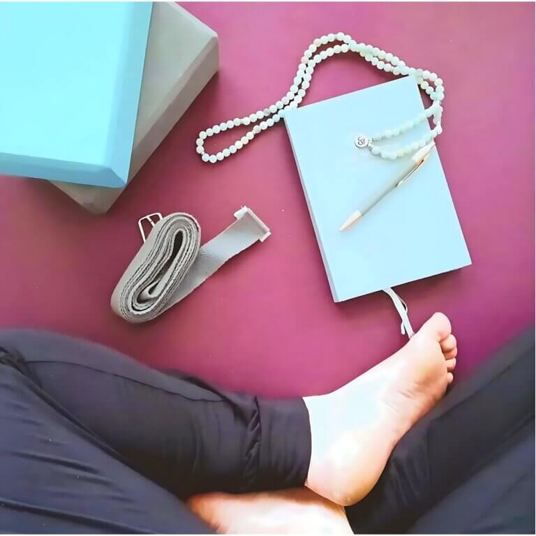 top view showing a woman sitting on a yoga mat. about to start yoga journaling