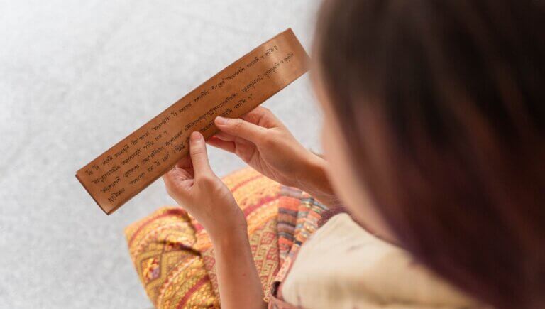 downward view of a woman reading sanskrit yoga terms and translating into english