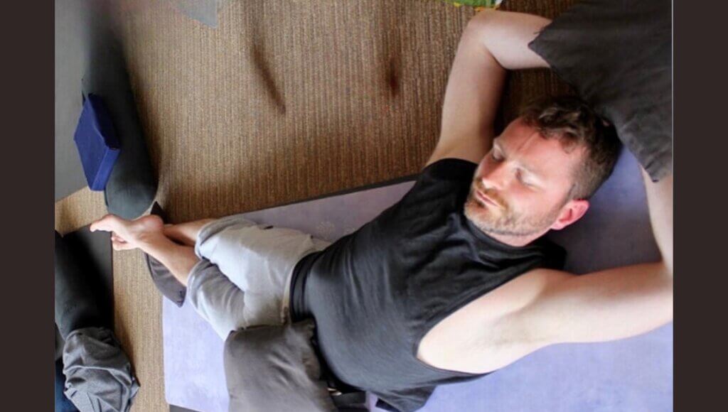 kevin parenteau doing bananasana pose with sandbags on feet hips and hands