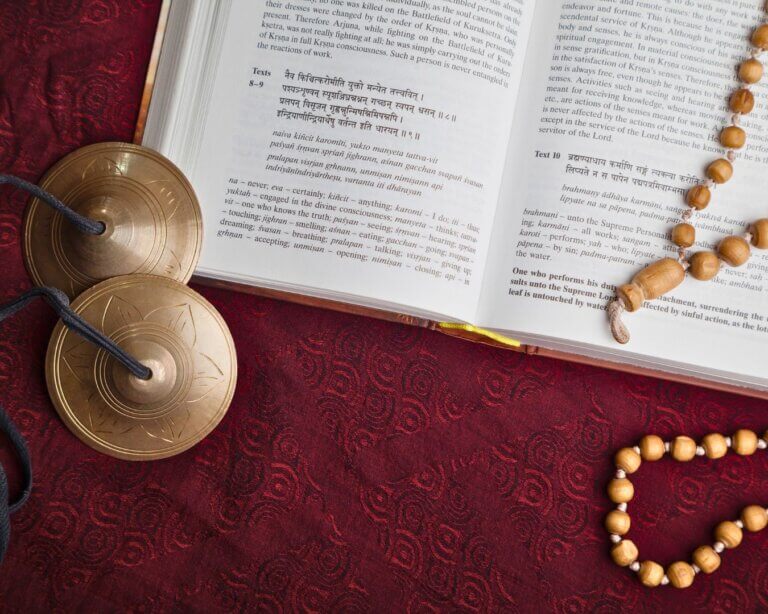 Open yoga philosophy book with mala beads and candle Learning about Hatha