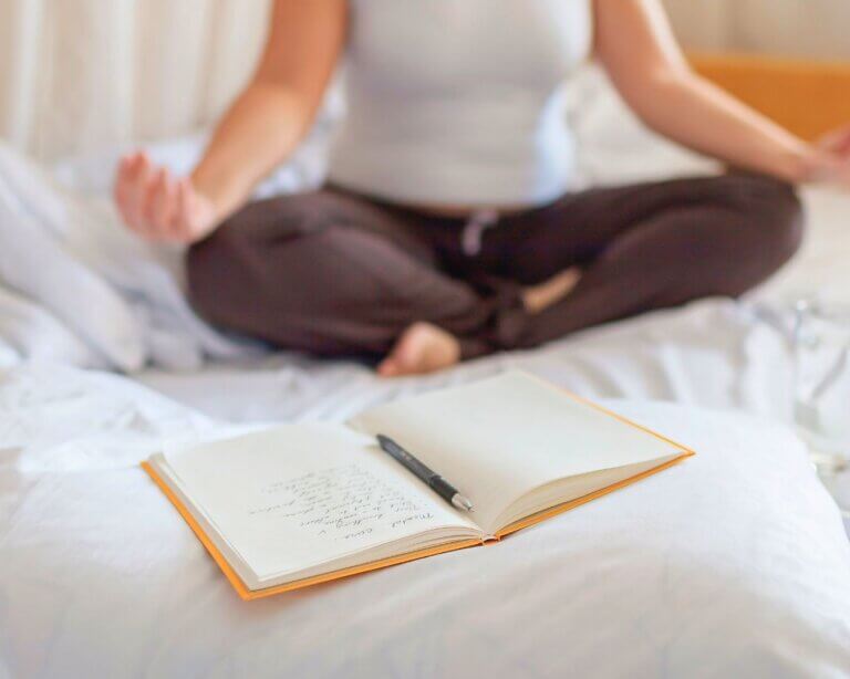 Hatha Yoga teacher writing a class plan with yoga mat and props beside