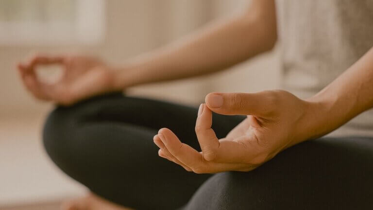 Close-up of hands resting on lap during meditation in natural light with a calm, serene atmosphere.