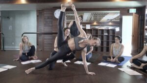Yoga teacher assisting a student during a training session, demonstrating how embodied learning develops through guided exploration.