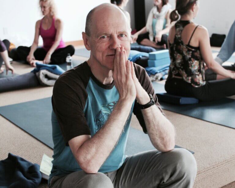 Bernie Clark, Yoga teacher sitting calmly hands in prayer during class