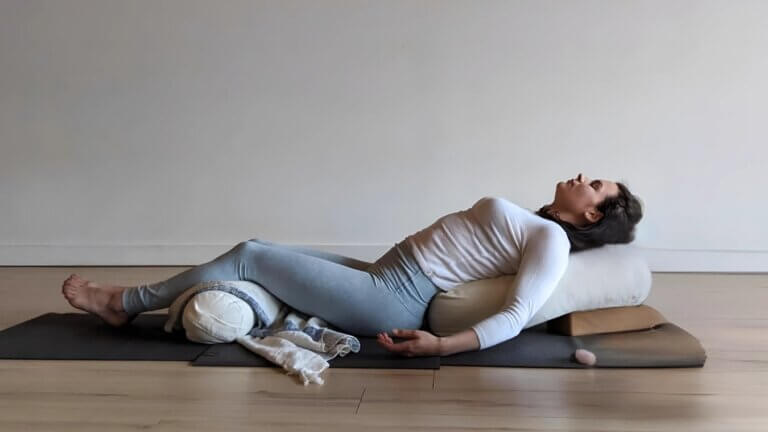 woman in a supported butterfly restorative yoga pose.