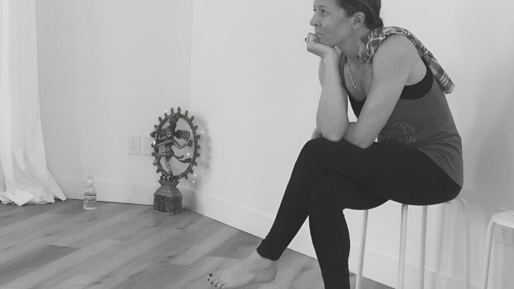Fiona Stang sitting quietly in reflection beside a yoga altar