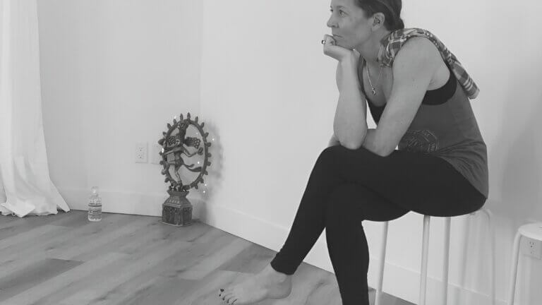 Fiona Stang sitting quietly in reflection beside a yoga altar