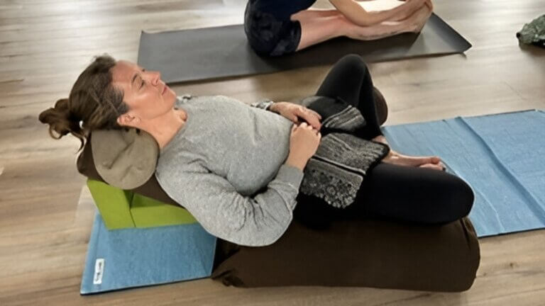 Fiona Stang practicing restorative yoga with props during perimenopause