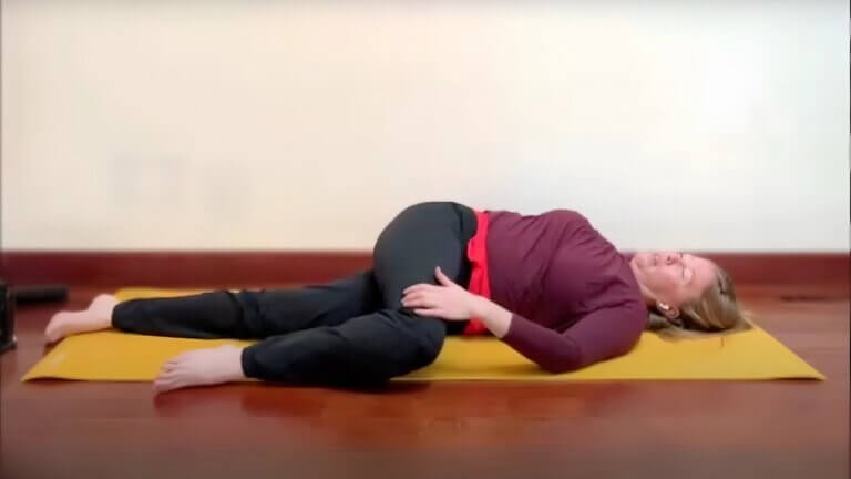 Diana Batts doing a one leg bent one leg straight yin yoga reclining twist pose