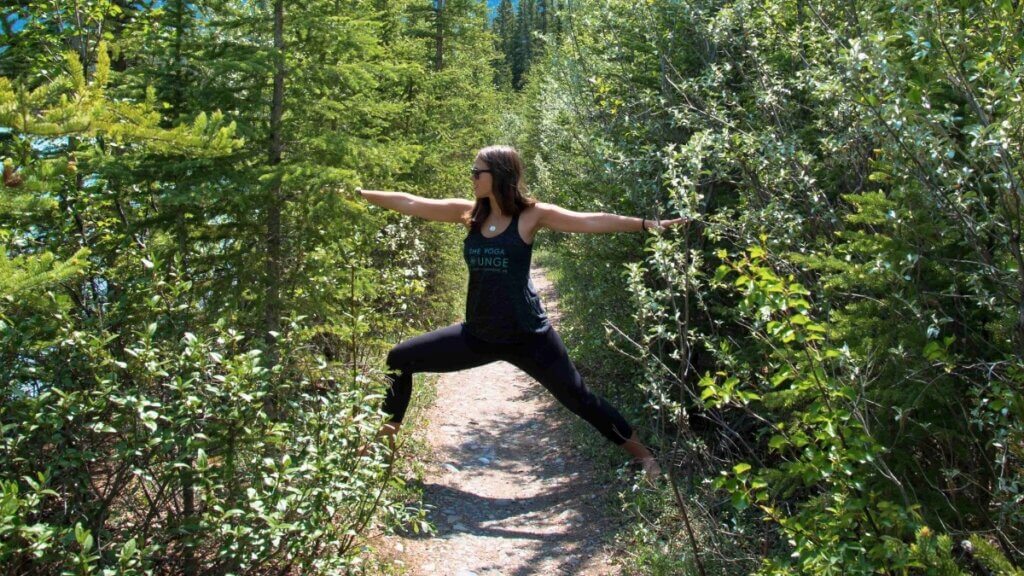 Amanda Kingsmith practicing Warrior II on a forest trail for a yoga business roadmap article