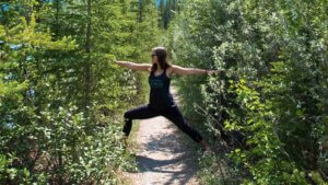 Amanda Kingsmith practicing Warrior II on a forest trail for a yoga business roadmap article