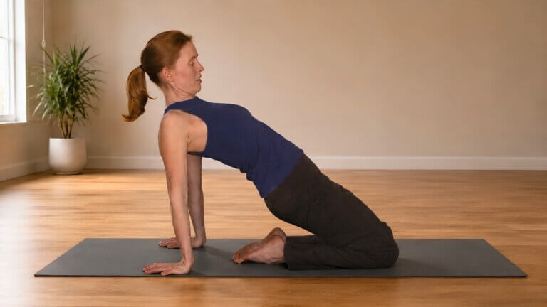 Diana Batts demonstrating a hands-to-floor variation of Camel Pose in a yoga studio