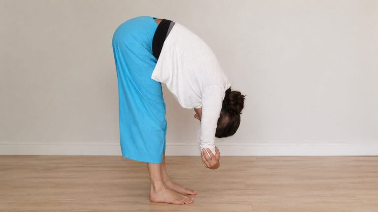 Side View of a woman doing dangling yoga pose grabbing opposite elbows