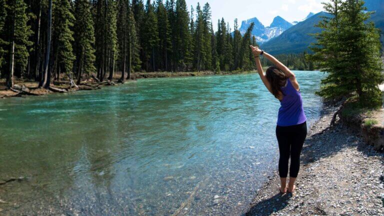 Amanda Kingsmith practicing a standing crescent moon pose beside a mountain river.