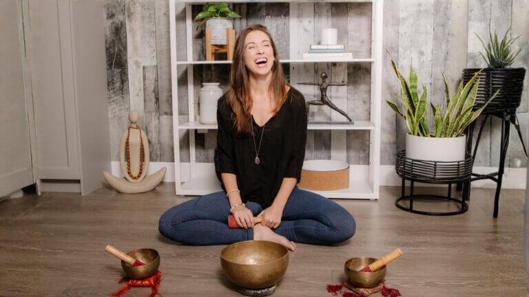 Christina Raskin seated cross-legged with singing bowls during a gentle yoga and meditation practice.