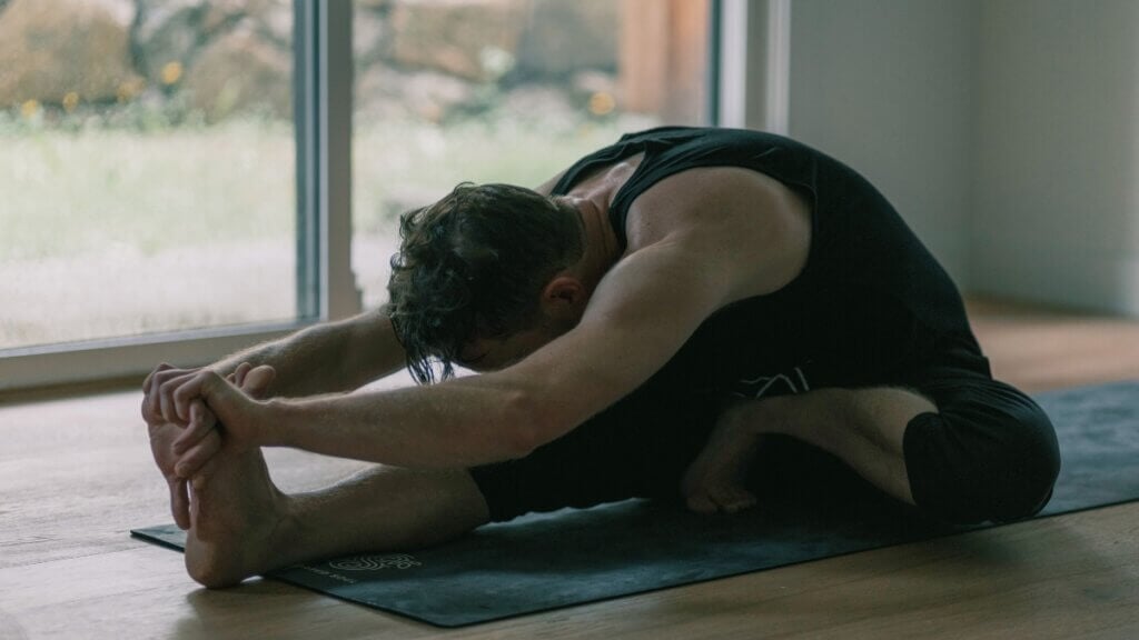 Kevin folding forward over his extended leg in Janu Sirsasana C.
